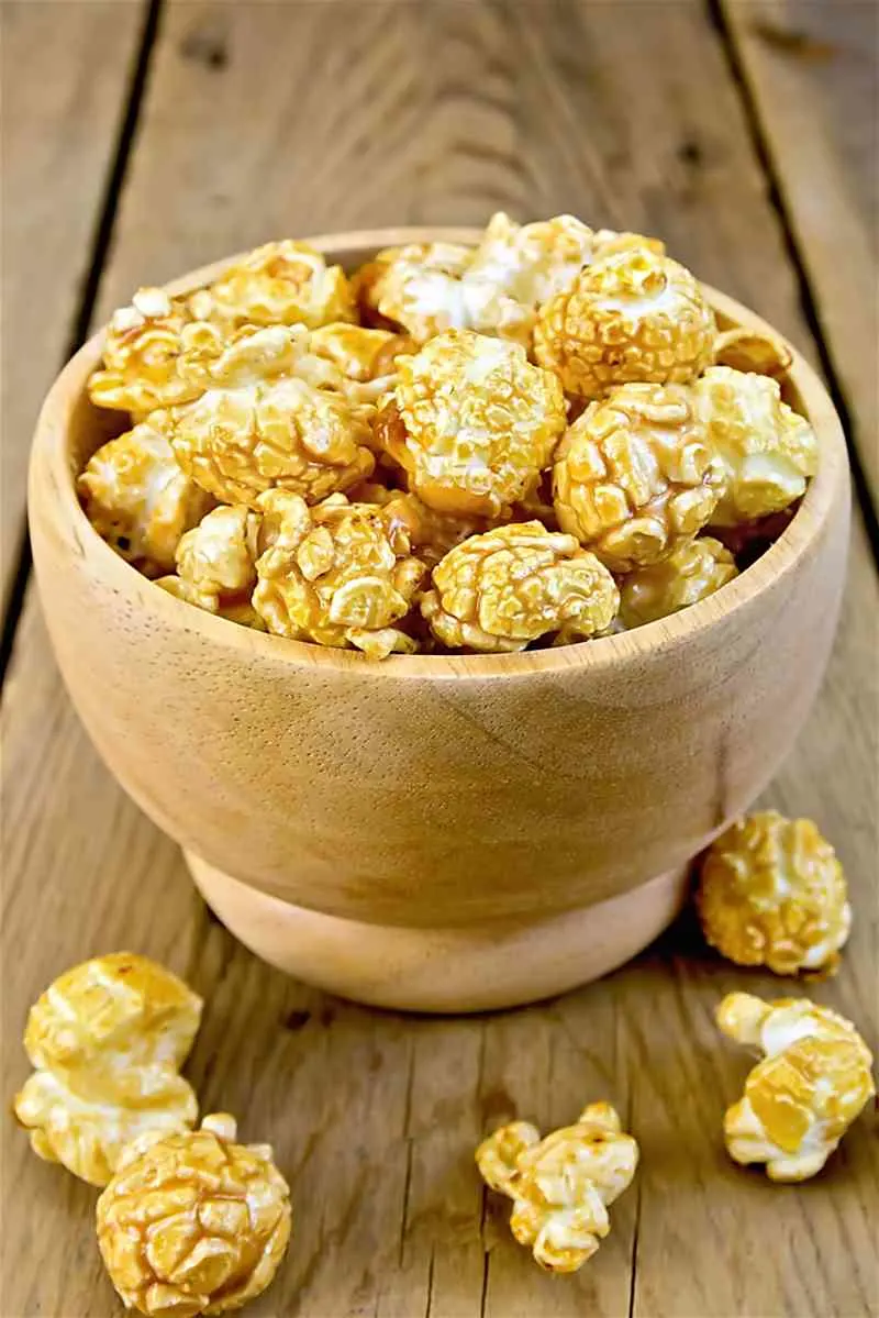 Koval Whiskey Cracker Jack Popcorn on wooden table in a wooden bowl with few popforn scatter around