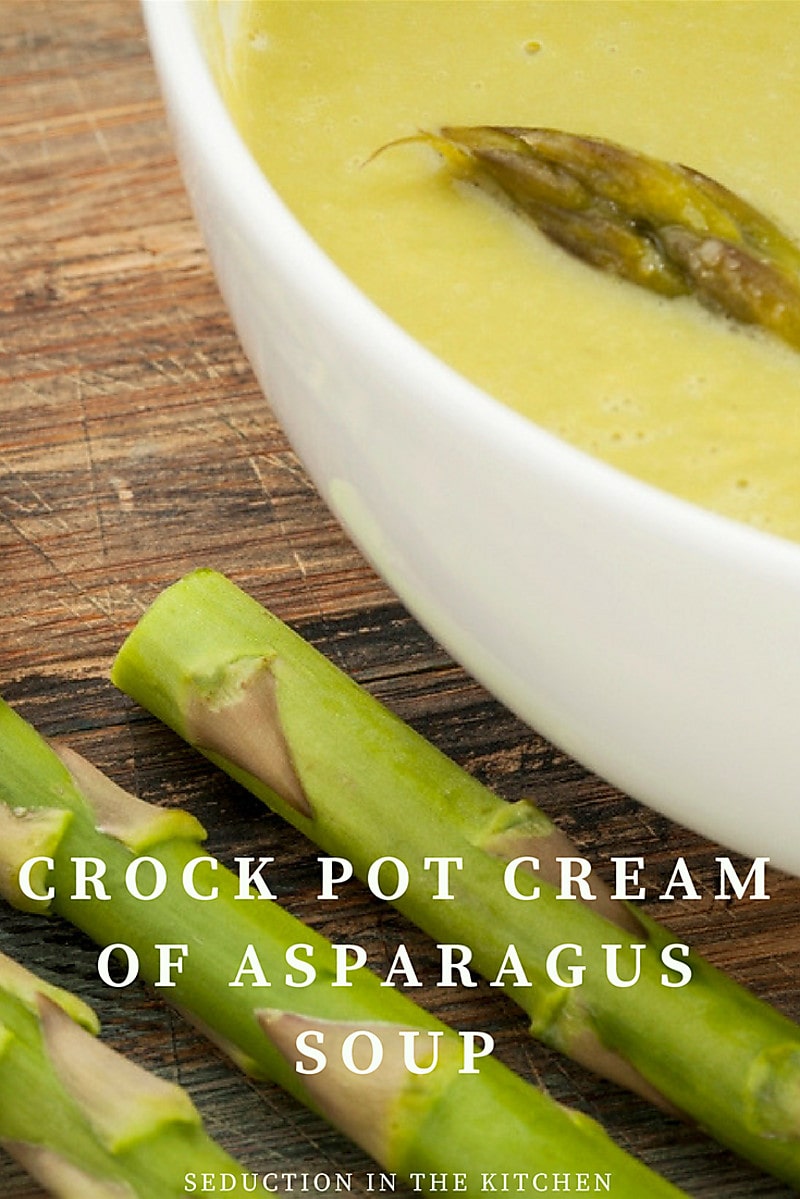 Crock Pot Cream Of Asparagus Soup in white bowl on table with asparagus