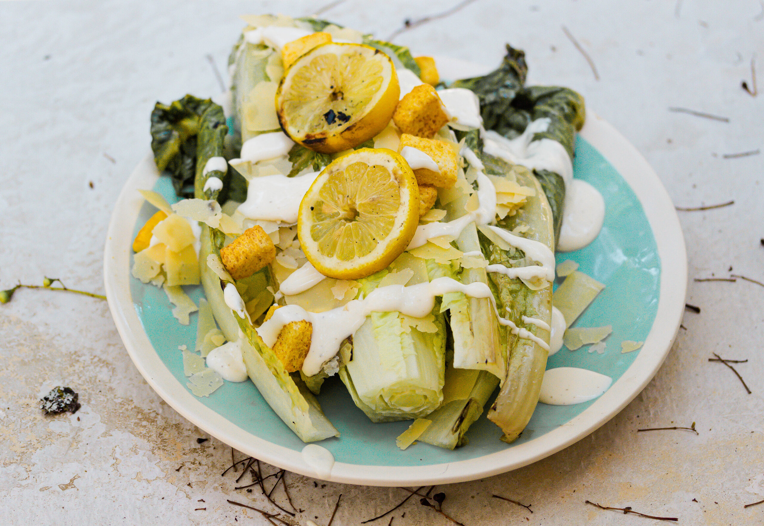 grilled romain with lemons on a blue plate