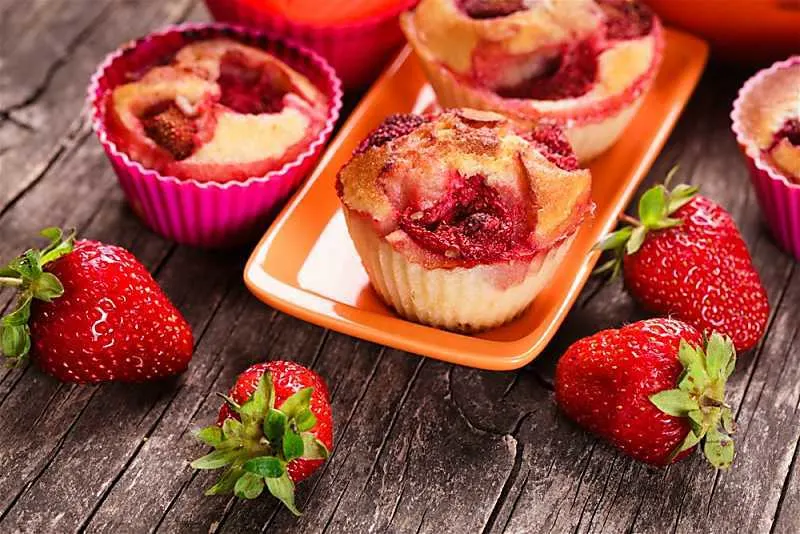 Looking for a breakfast pastry to enjoy in the morning? Mango Strawberry Muffins is so simple to make with fresh fruit. The mango strawberry muffins only take one bowl to make. Mango strawberry muffins on wooden table on tangerine plate and muffin liners
