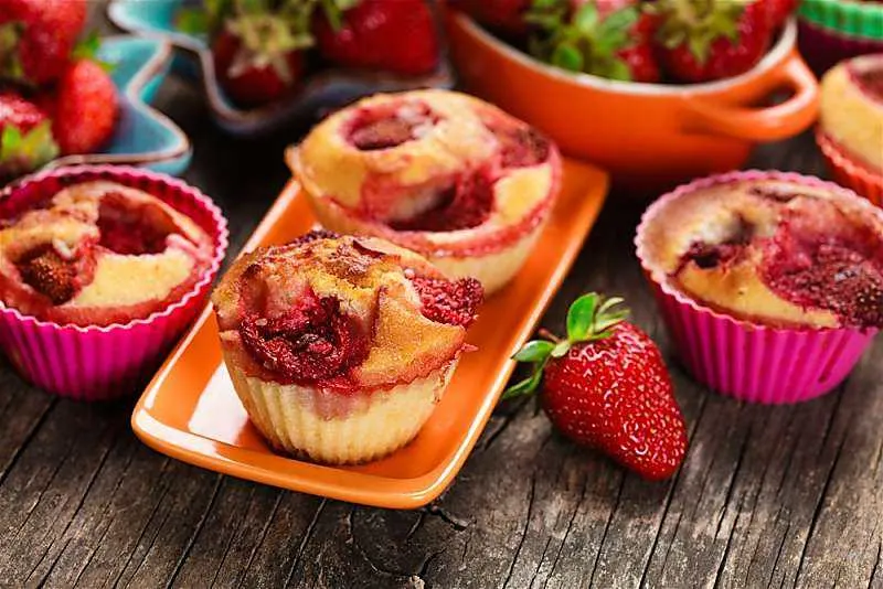 Mango Strawberry Muffins is so simple to make with fresh fruit. The mango strawberry muffins only take one bowl to make. 2 Mango strawberry muffins on tangerine colored plate