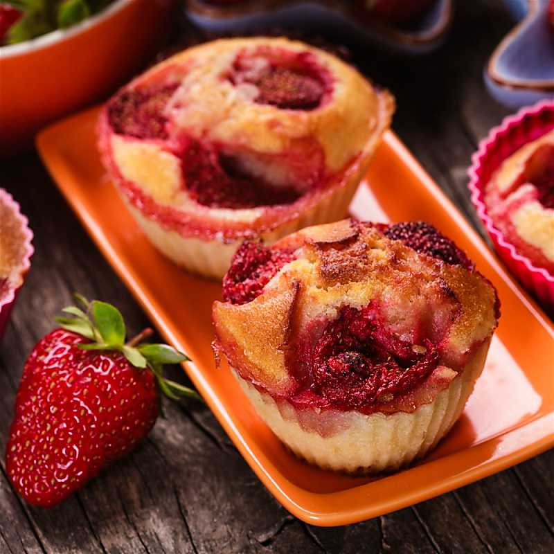 Mango strawberry muffins on tangerine colored plate on table with strawberries