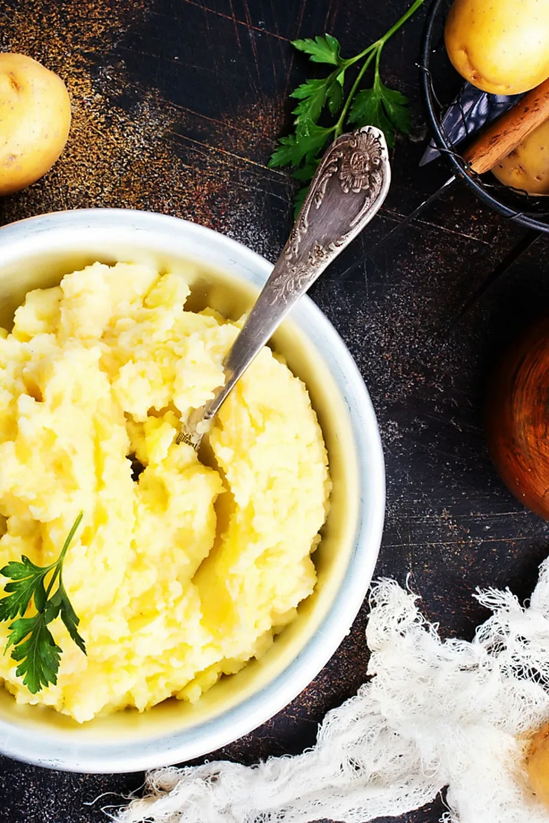 Ricotta Mashed Potatoes in white bowl with bluw trim on dark brown table