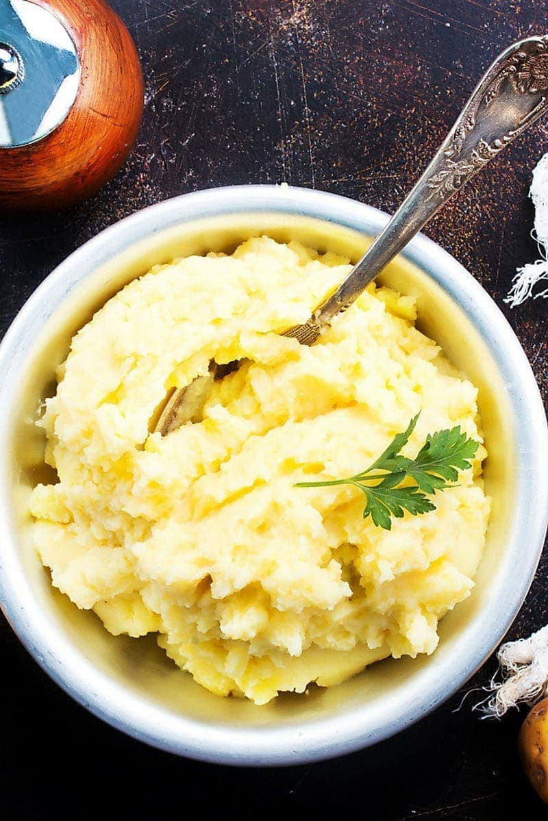 Ricotta Mashed Potatoes in white bowl on table with spoon in potatoes