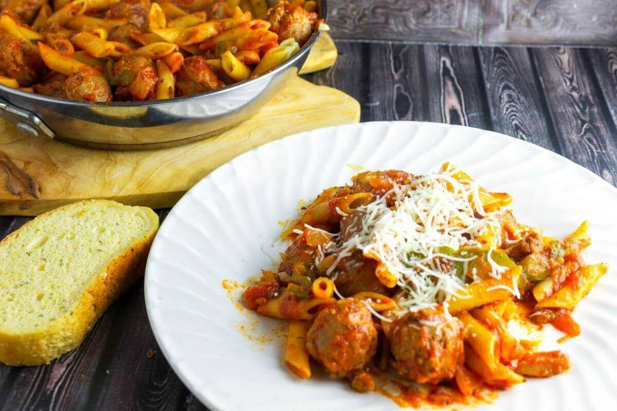 Sausage and Peppers Mostaccioli With a skillet and white plate on table