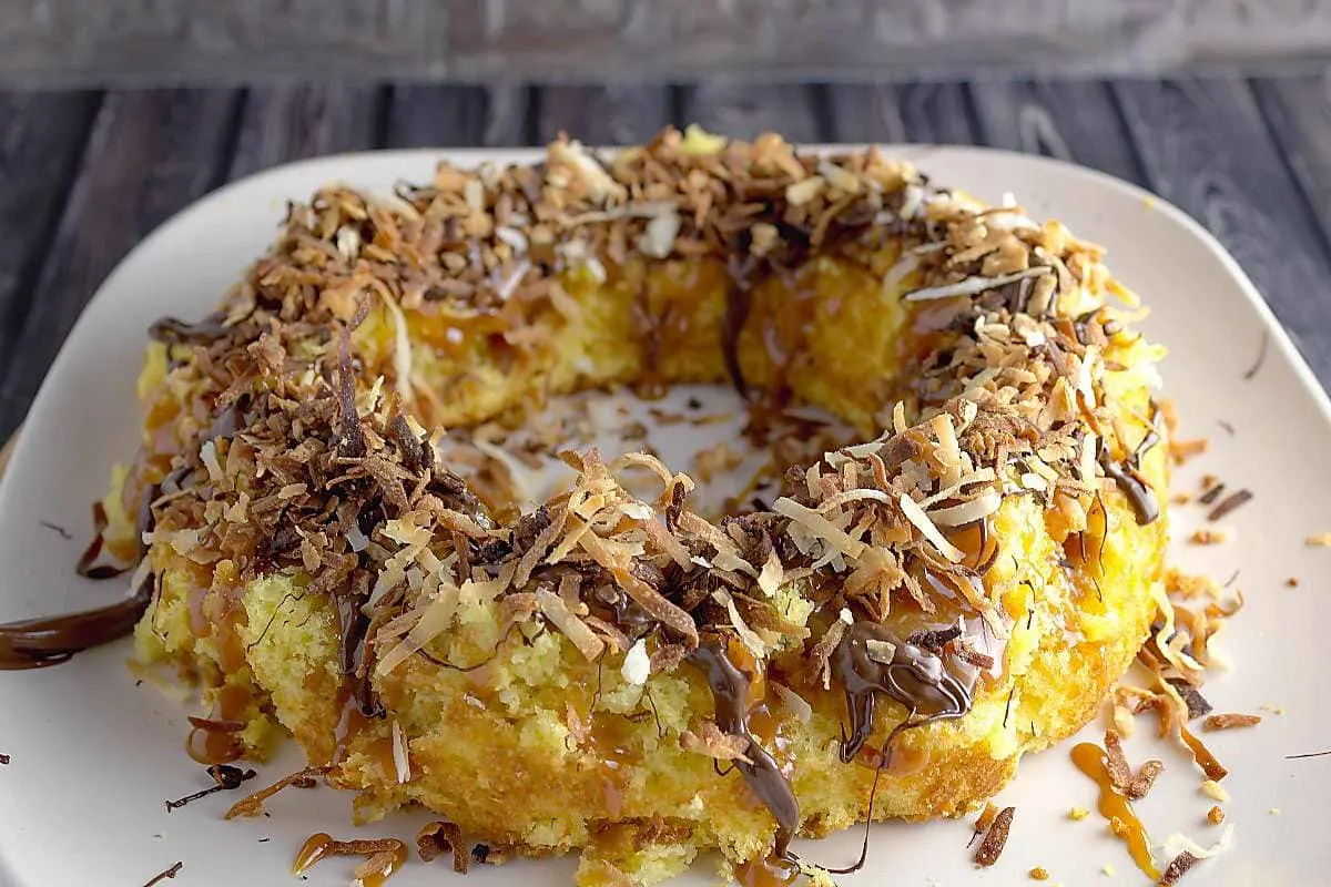 Girl Scouts Caramel Delites Bundt Cake Recipe is the cake version of the famous Girl Scout Samoas cookie. One bite and you will fall in love with it Girl-Scouts-Caramel-Delites-Bundt-Cake-Recipe on table on a plate
