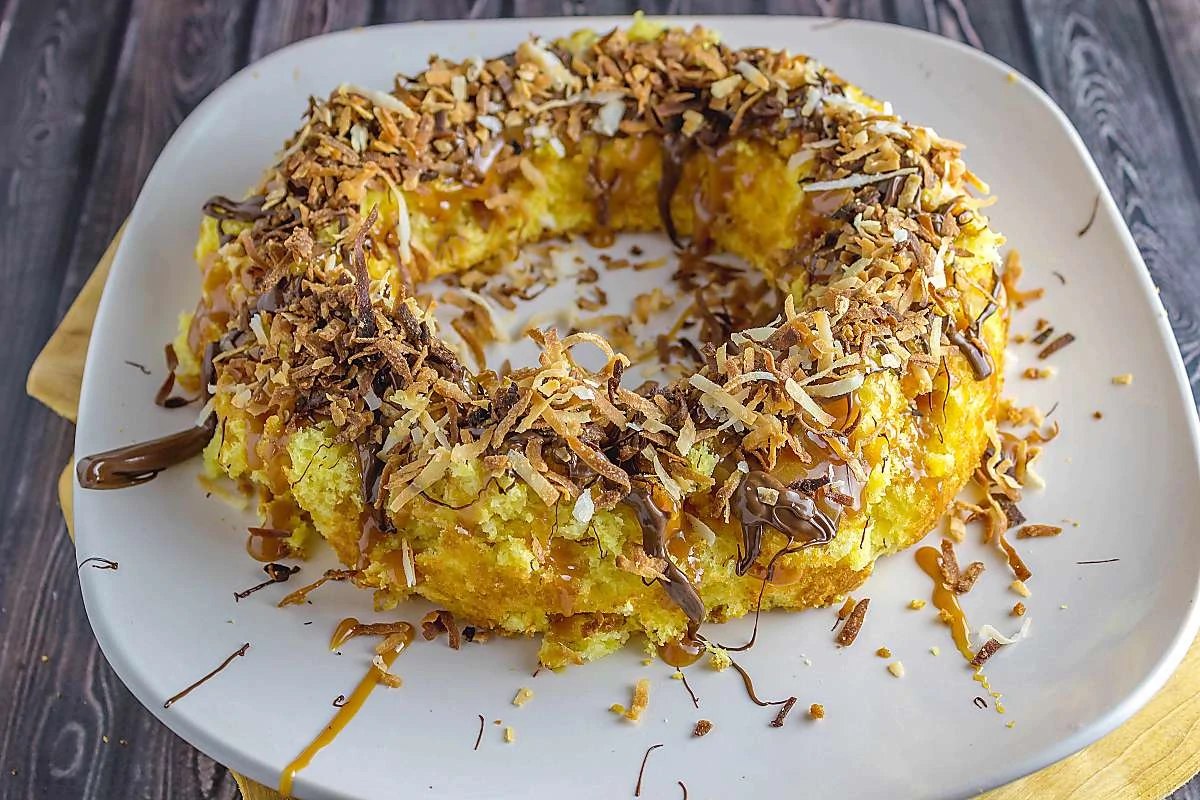 Girl Scouts Caramel Delites Bundt Cake Recipe is the cake version of the famous Girl Scout Samoas cookie. One bite and you will fall in love with it Girl-Scouts-Caramel-Delites-Bundt-Cake-Recipe Wide shot of cake on plate
