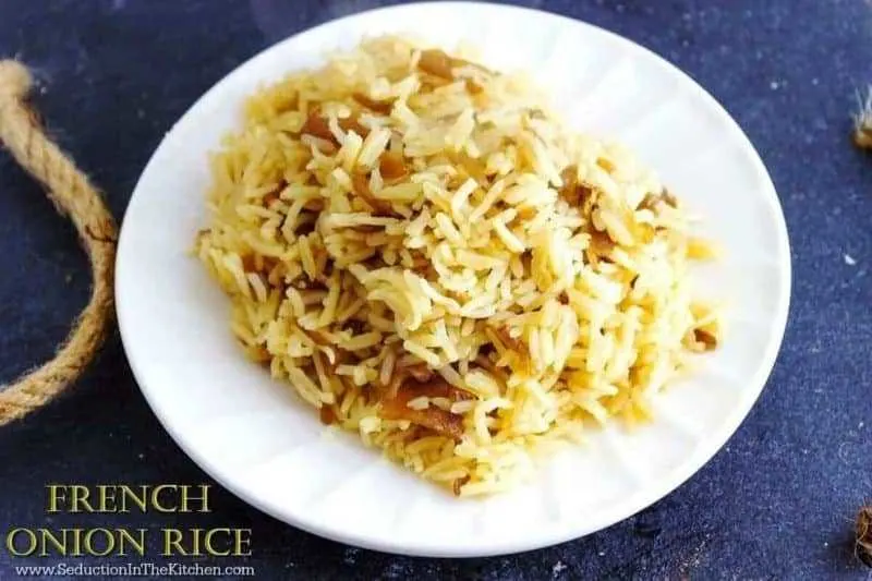 French Onion Rice on a white plate on dark slate and a rope