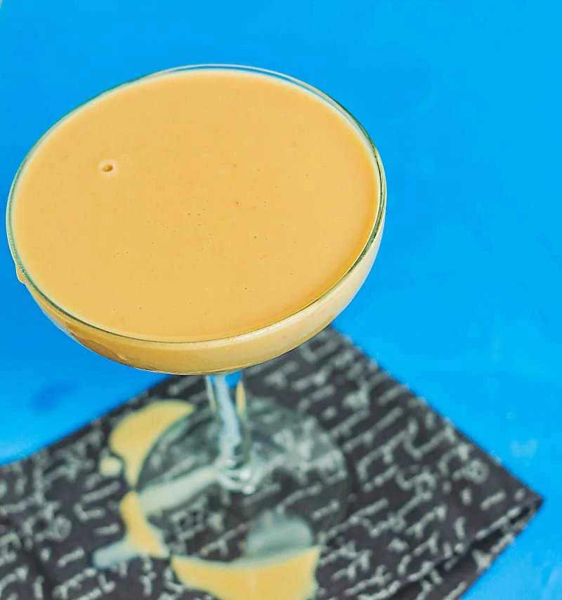 Creamsicle margarita on blue background with a spill