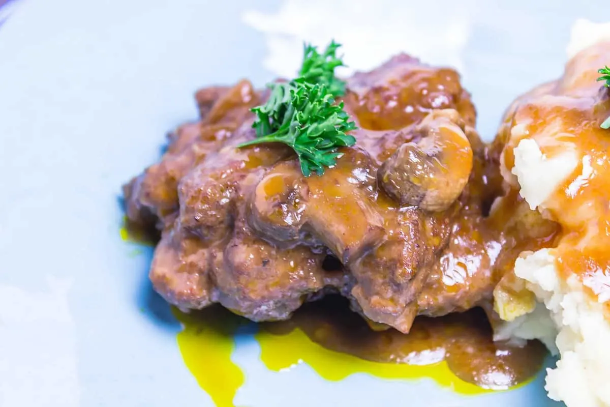 Slow Cooker Salisbury Steak is made with a rich, tangy gravy that is made in the slow cooker and is perfect for a busy family dinner! Slow Cooker Salisbury Steak close up of steak with gravy