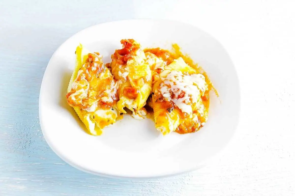 Italian Cheese Stuffed Shells is covered with tomato sauce and baked to perfection. Italian Cheese Stuffed Shells in a white dish on a table