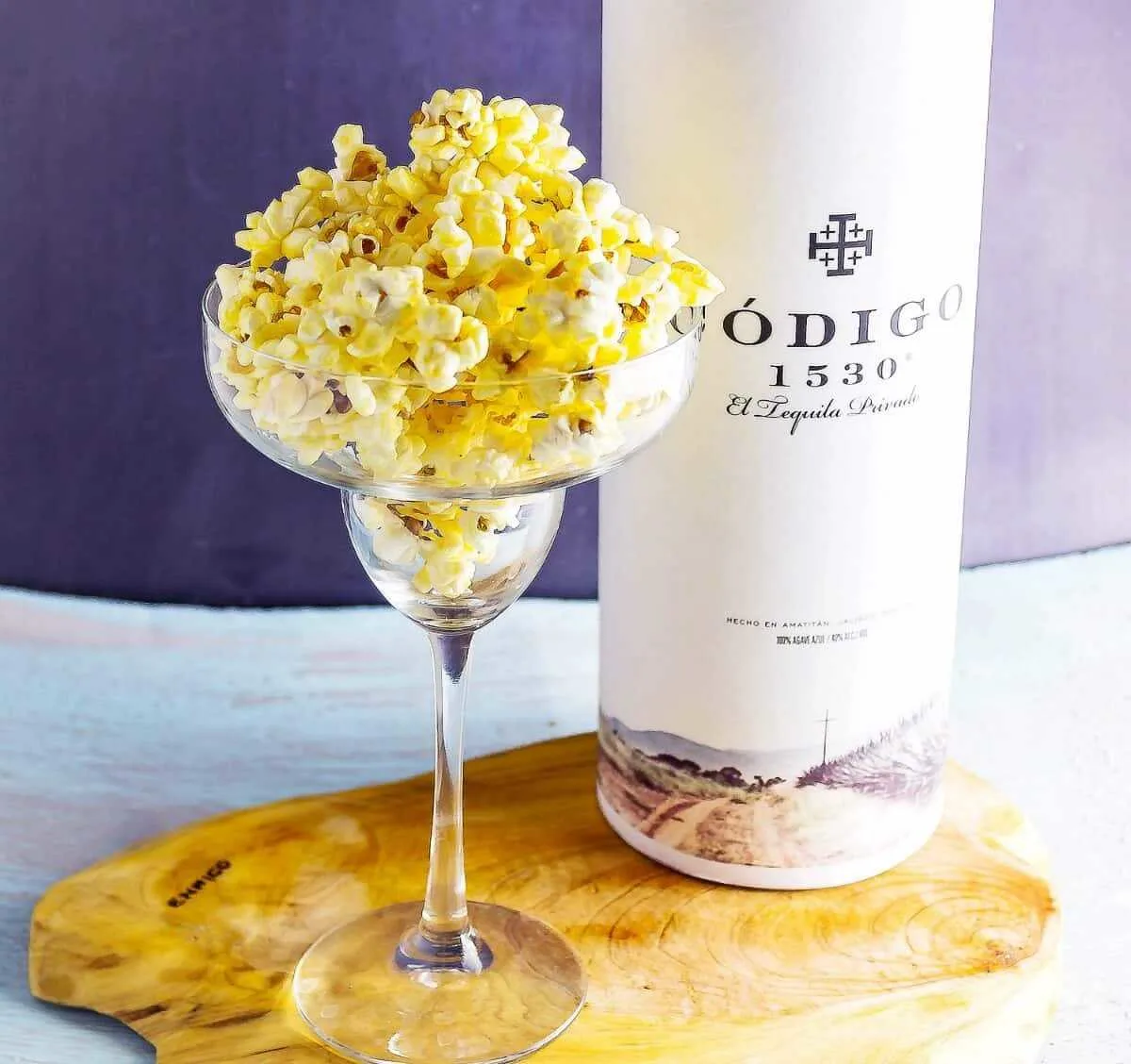 Margarita Glazed Boozy Popcorn in margarita glass with bottle tequila