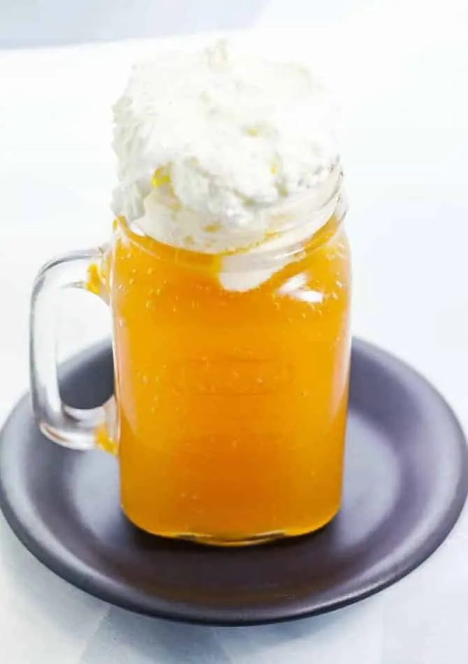 Butterbeer in a mason jar mug with whipped foam topping on black plate