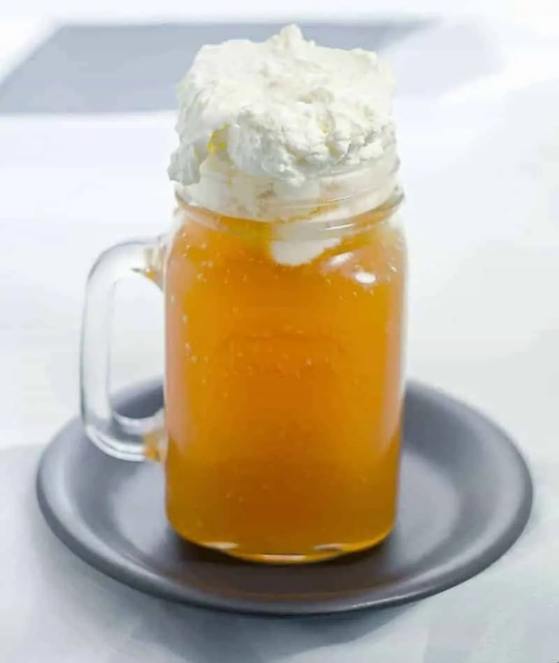 Butterbeer in a mason jar mug with whipped foam topping on black plate