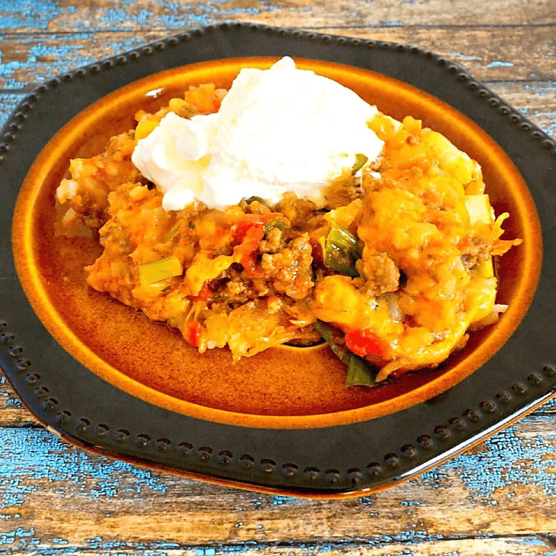 Hash Brown Ranchero Taco Bake on brown plate on weathered blue table