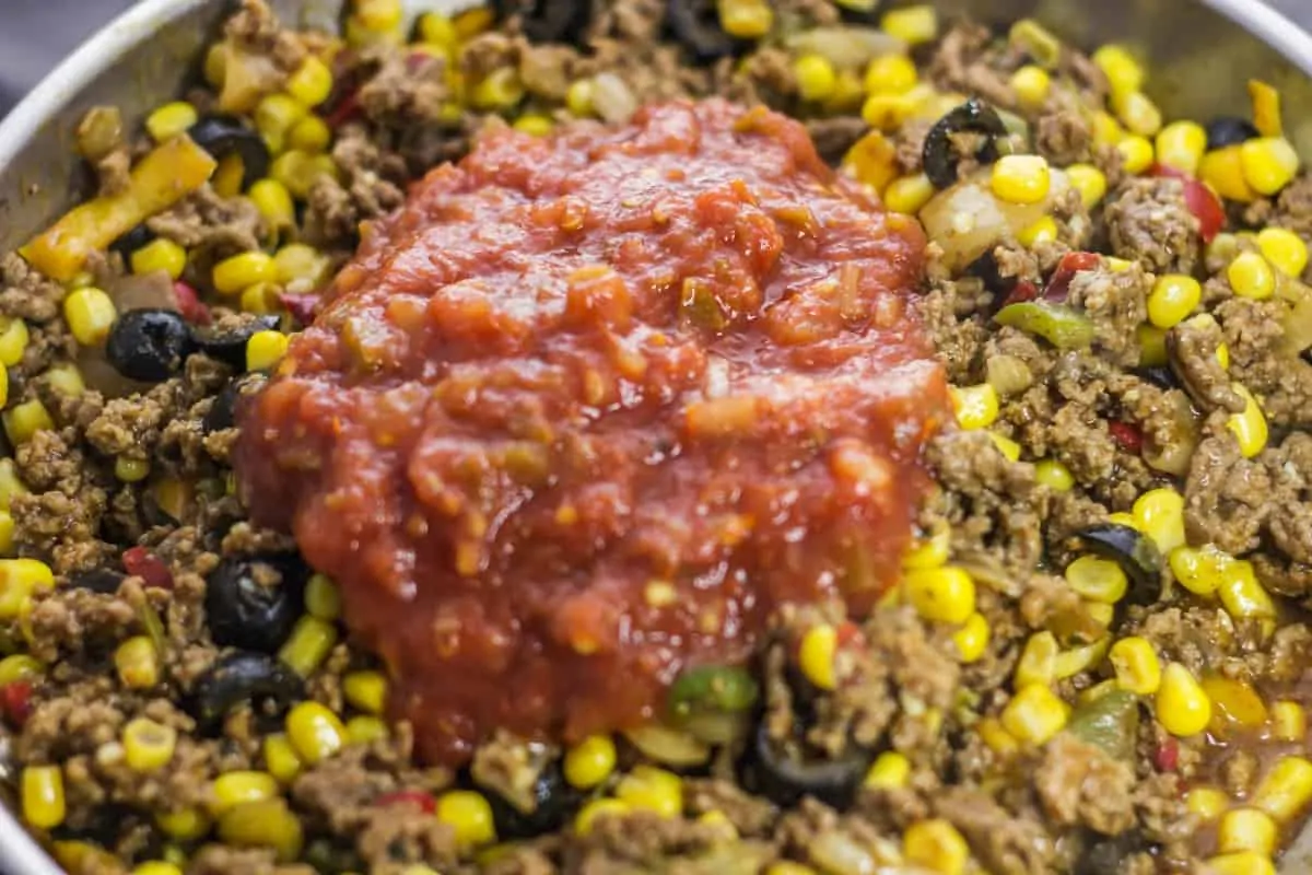 Salsa being added to filling of taco pot pie