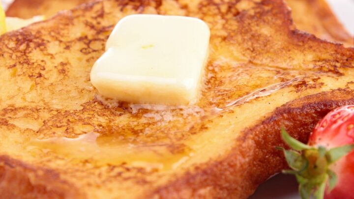 French toast with butter and strawberries on white plate