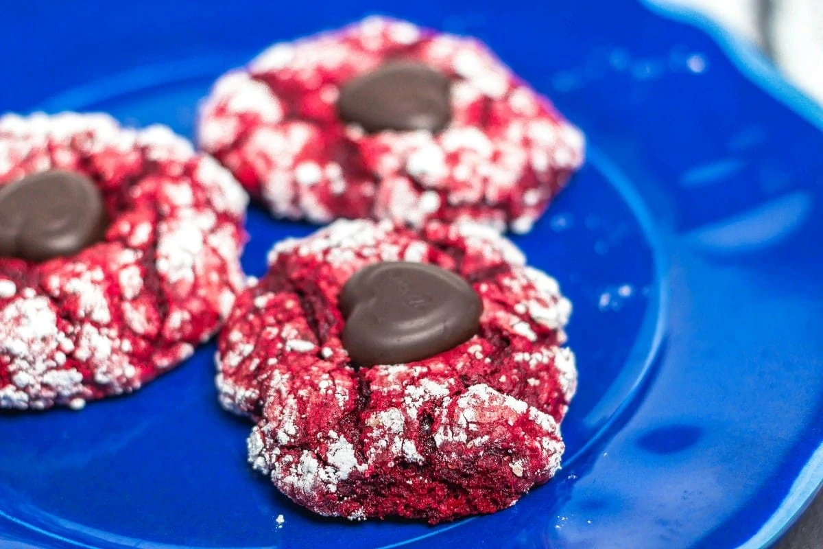 Valentine Red Velvet Cake Mix Blossoms are easy to make and is 5 ingredients! It combines the crinkle cookie with a blossom cookie for a yummy Valentine's Day Treat! Valentine Red Velvet Cake Mix Blossoms close up of 3 cookies