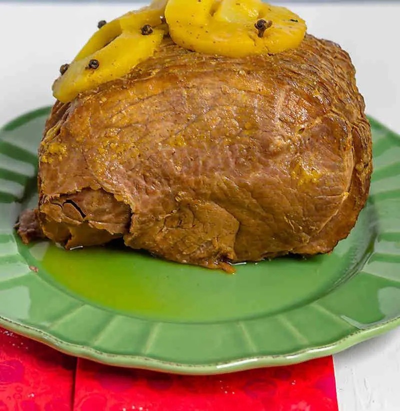 Instant Pot Pineapple Mango ham! It is a simple way to make a holiday ham. Instant Pot Pineapple Mango Ham on green plate with pineapples on top