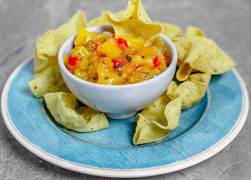 mango salsa on blue plate in a white bowl with chips