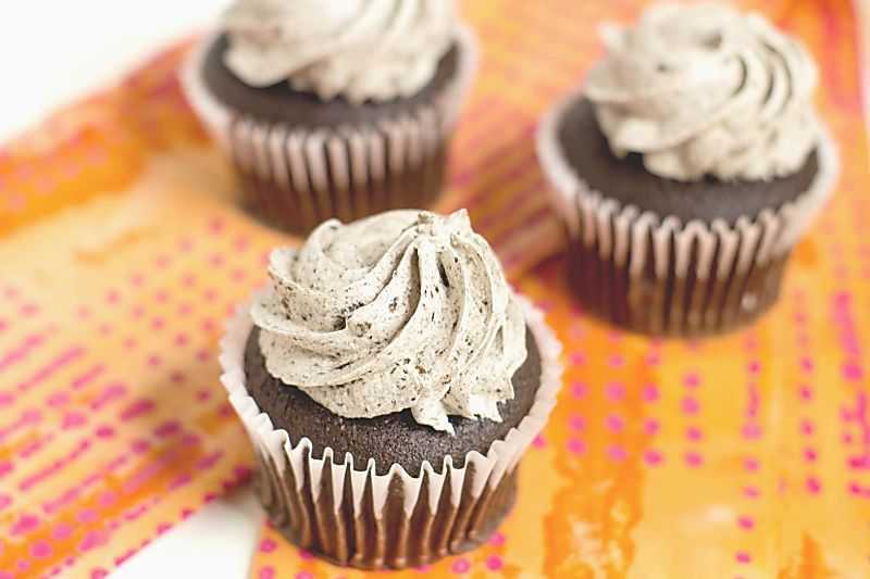 Close up view of 3 grey stuff cupcakes on orange napkin