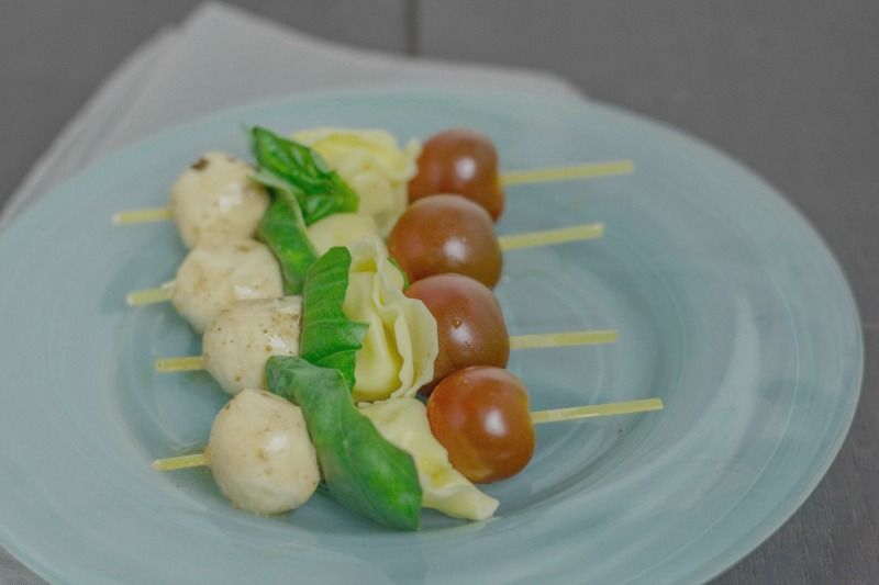 Caprese tortellini skewers on a blue plate