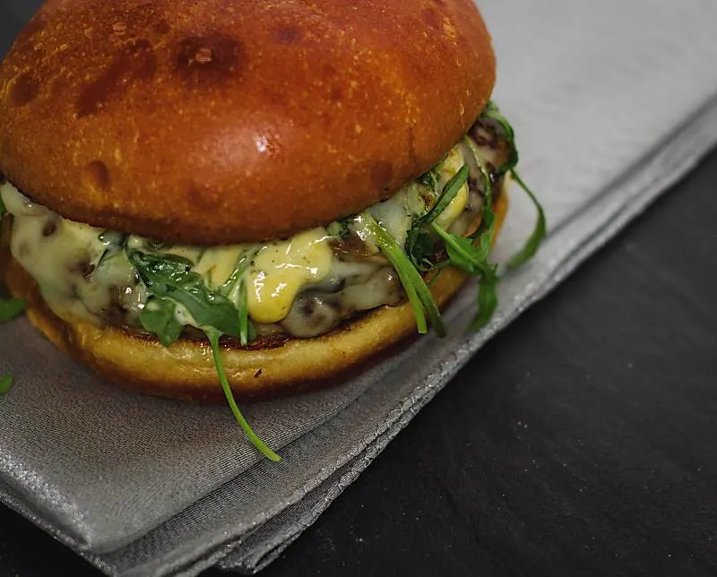 Pesto Portabello Chicken Burger on a silver table cloth on black table close up