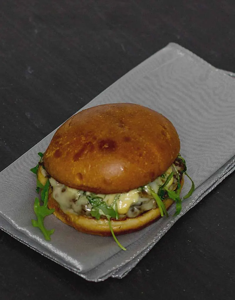 Pesto Portabello Chicken Burger on a silver table cloth on black table on an angle