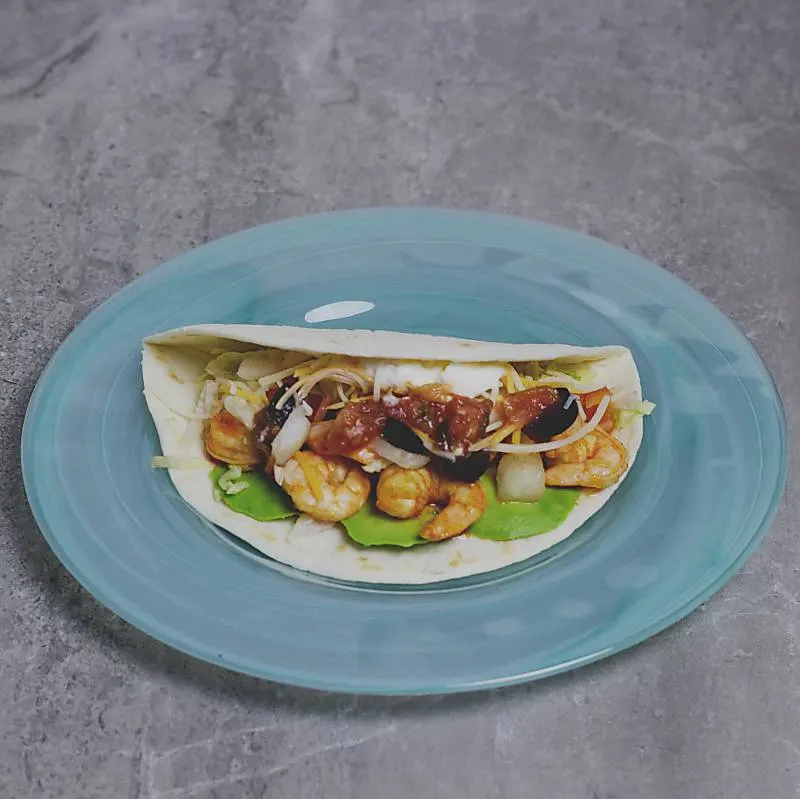 soft shell shrimp taco on blue plate on grey marble table top