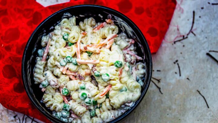 bacon ranch pasta salad in black bowl on red c;loth on grey stone