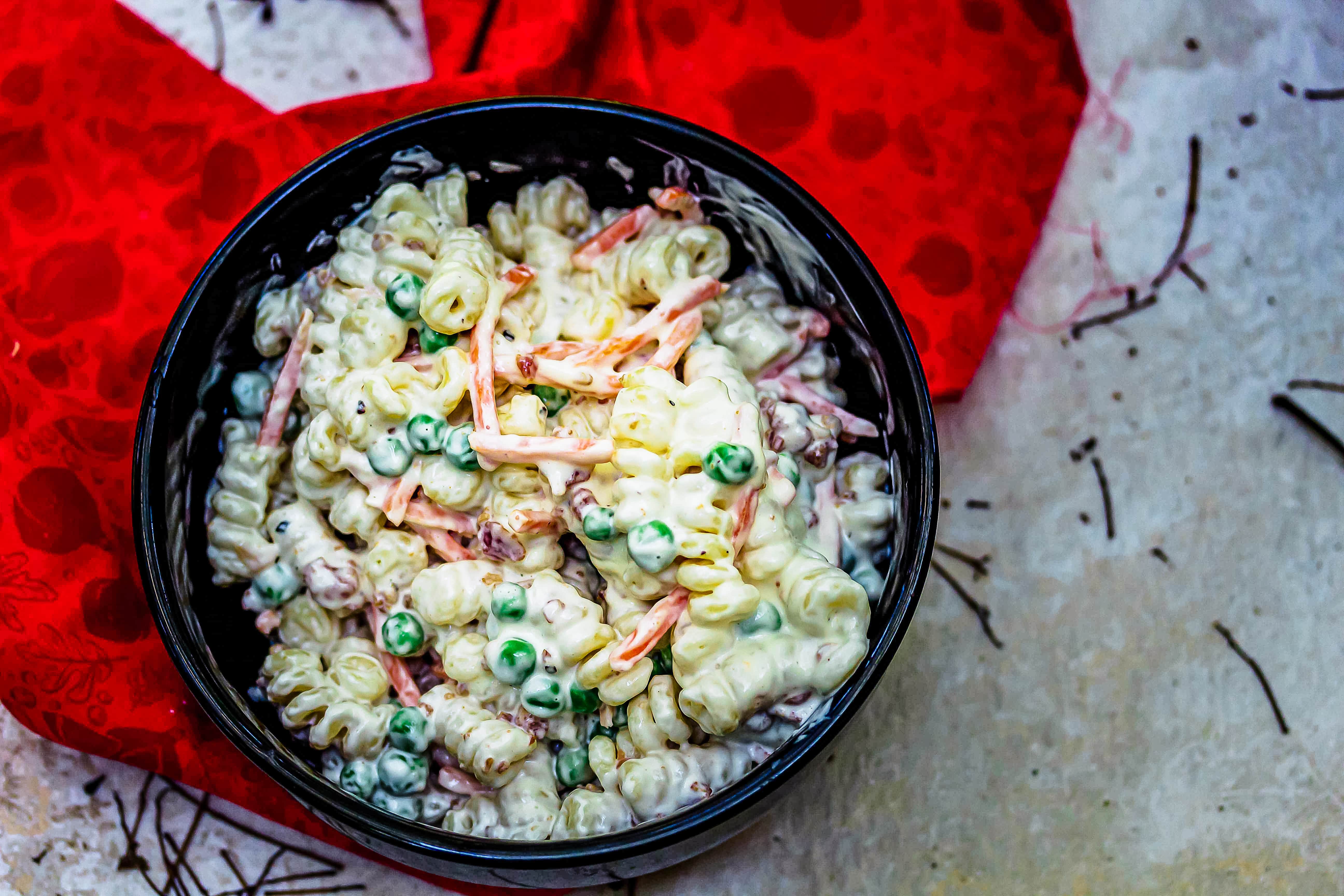 bacon ranch pasta salad in black bowl on red c;loth on grey stone