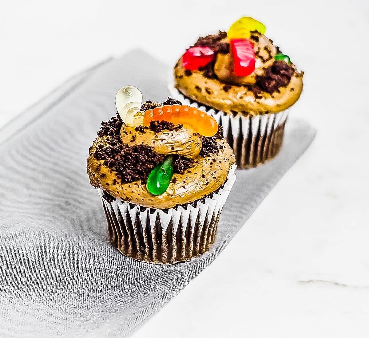 2 dirt and worms cupcakes on grey cloth