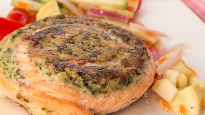 Spinach and Feta Pinwheel Salmon on white surface with vegetables