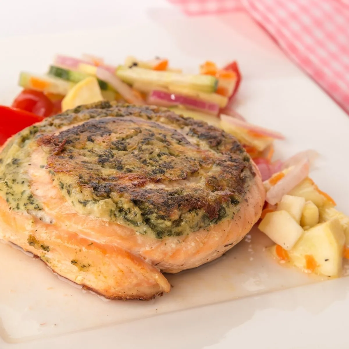 Spinach and Feta Pinwheel Salmon on white surface with vegetables