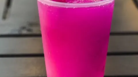 Violet Lemonade {A Simple Copycat Disney Recipe} violet lemonade in clear cup with violet on top on black table